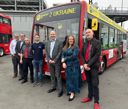 Transport UK London Bus team including volunteer drivers in front of donated london bus at the Battersea bus depot